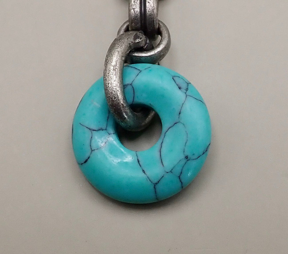 Turquoise pendant with silver chain on a light gray background